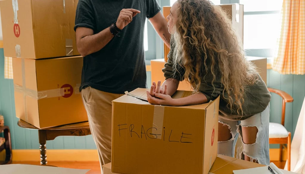man and woman talking to each other with boxes in the background