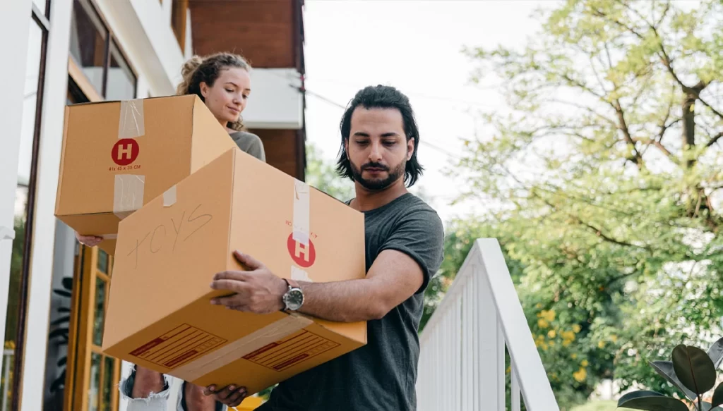 couple walking down starirs with boxes