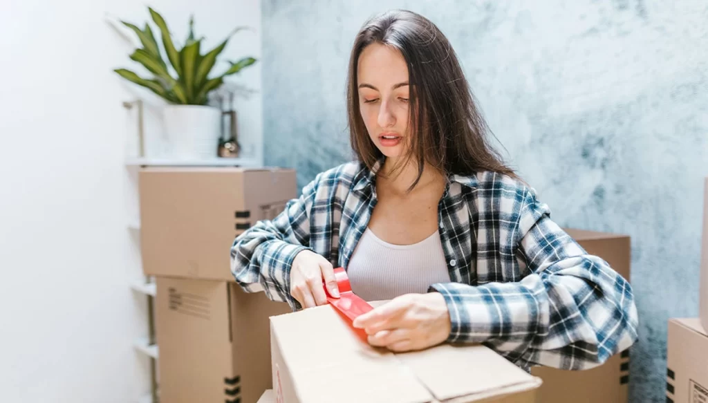 woman putting red tape on a box