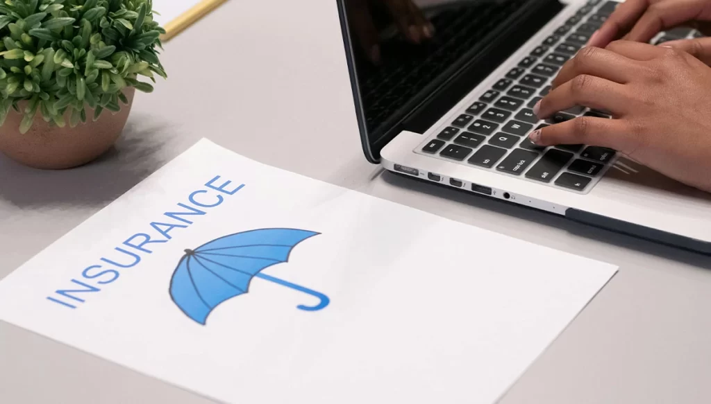 person at a desk with a laptop and paper that says insurance