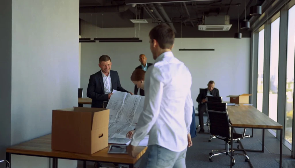 Office workers moving boxes into an empty office