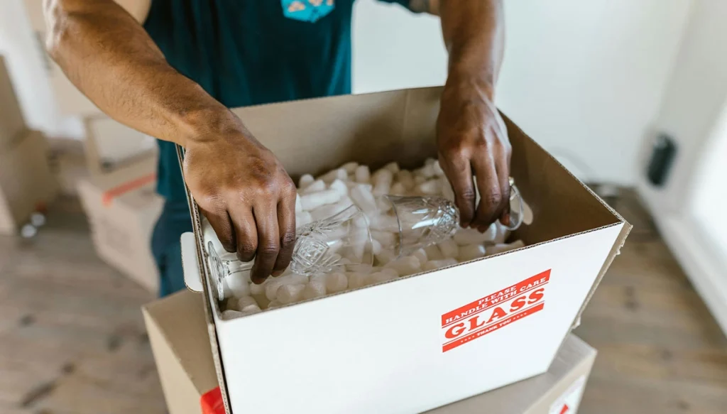hands placing fine glassware into a foam box