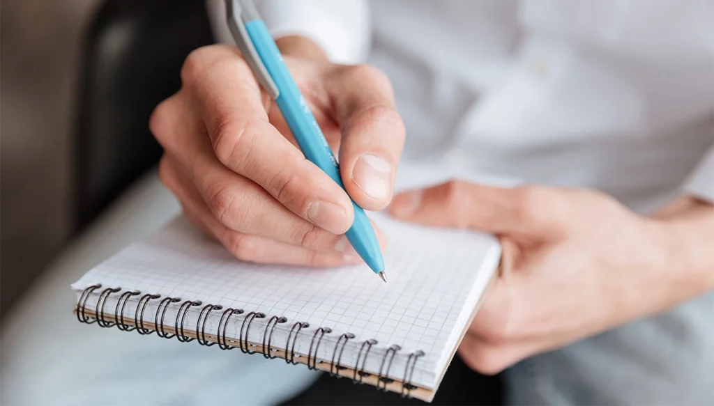 female hand writing on a notepad
