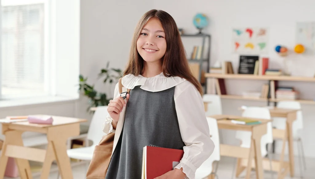 smiling girl in a classroom with a school bag